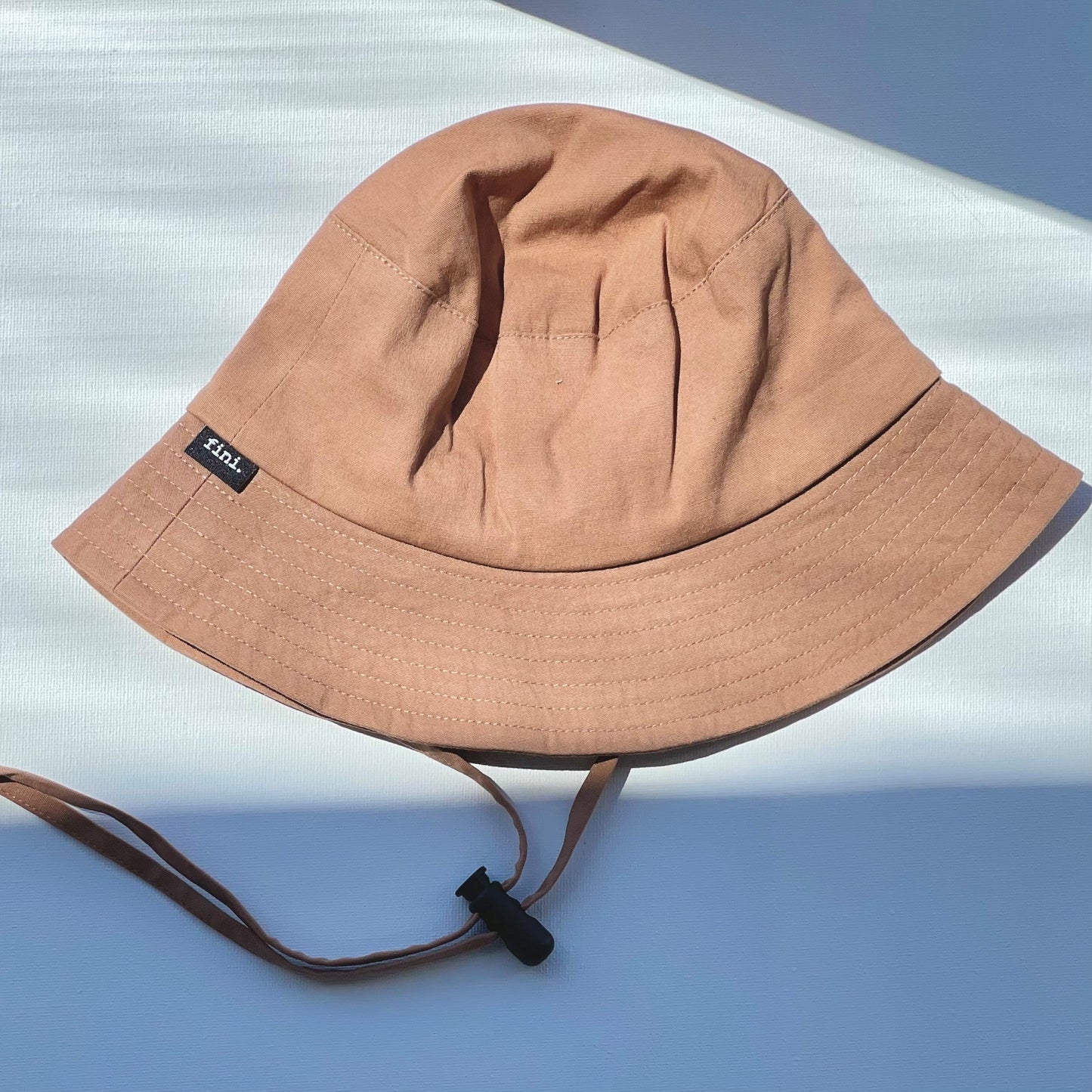 WS_available now_FINI. HAT: fini. bucket hat - mocha-fini. the label